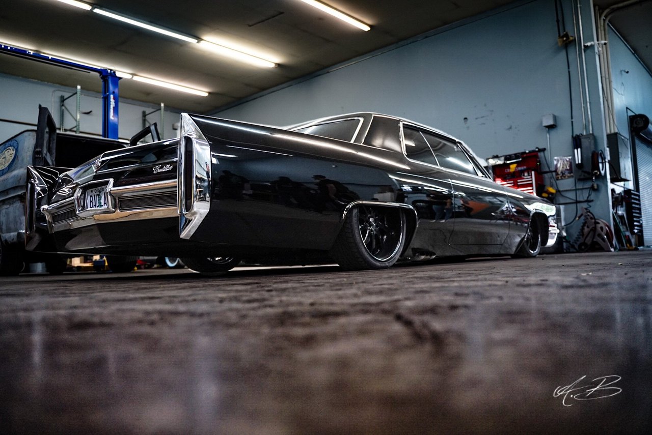 Black Cadillac sitting low on custom wheels in the shop, shot from floor level