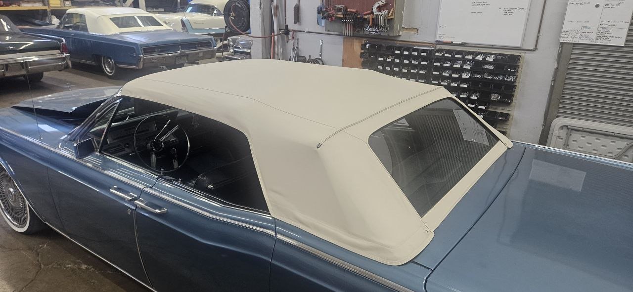 New white convertible top on a blue classic convertible in the shop
