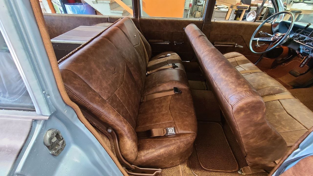 Rear and front bench seats in distressed brown leather, seen from the back door